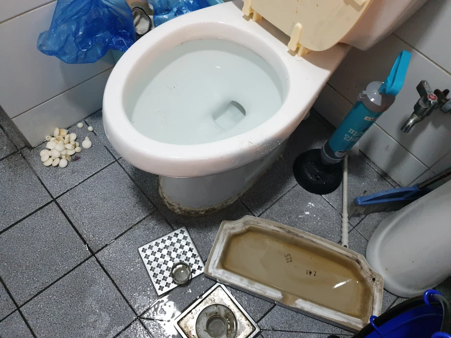 변기 분리 후 노출된 바닥 이음부, 변기와 공구가 함께 있는 현장