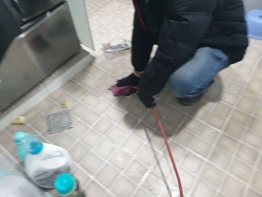 세정제 옆에서 붉은 호스로 화장실 바닥을 세척하는 모습