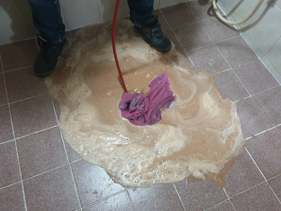 대걸레로 바닥에 넓게 퍼진 갈색 물자국을 닦는 모습
