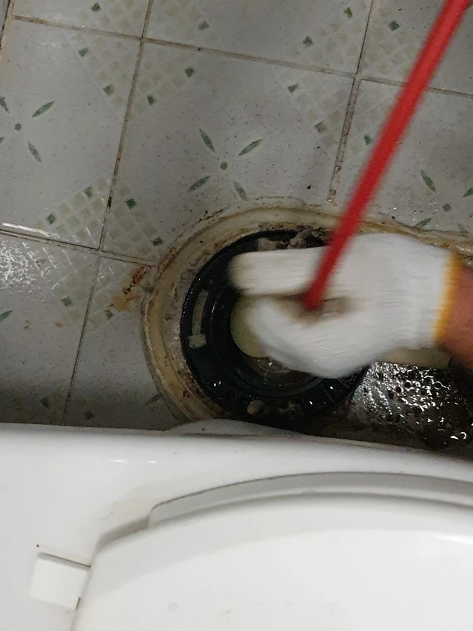 변기배관막힘 관련 확인, 배관 구멍에 케이블을 넣는 손 클로즈업
