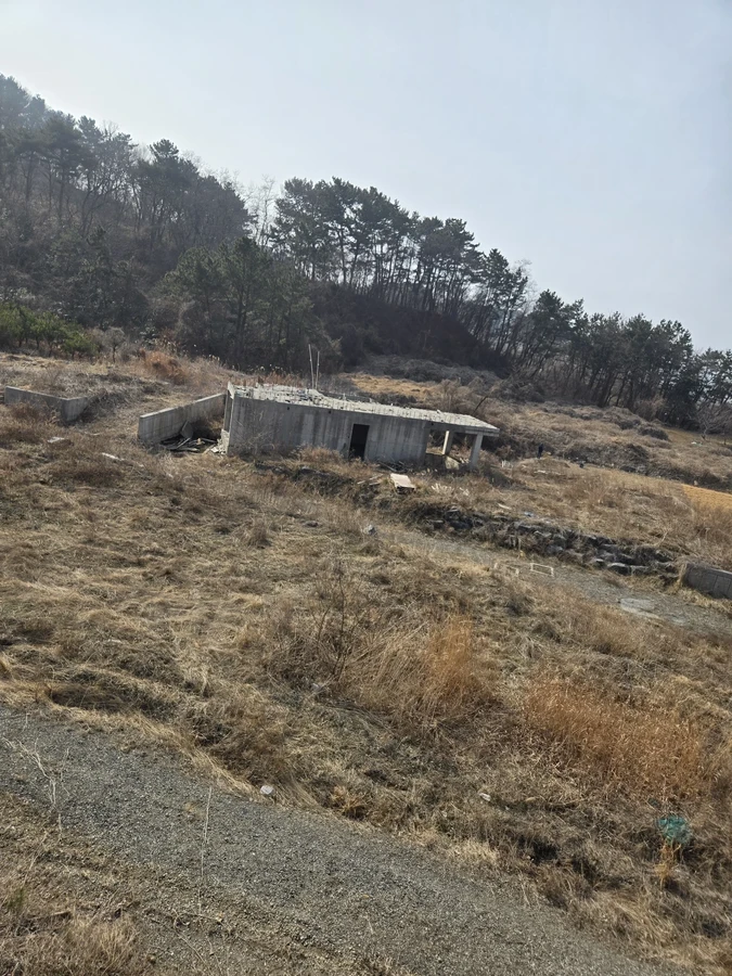 경사진 마른 풀 부지 위에 작은 콘크리트 구조물이 놓여 있는 모습
