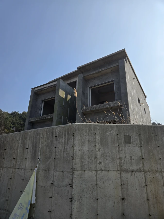 낮은 각도에서 본 옹벽 위 철근콘크리트 2층 구조물의 외관